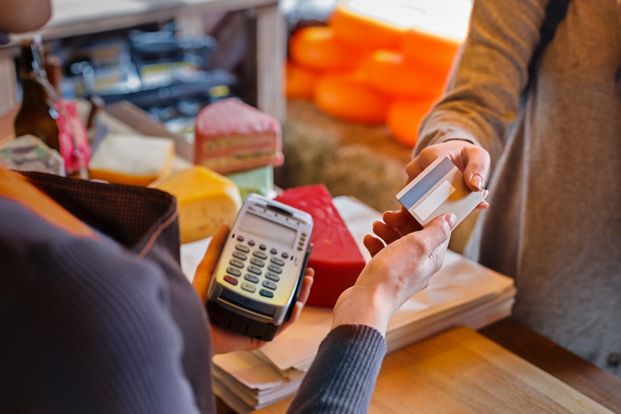 Customer paying for order of cheese in grocery shop.