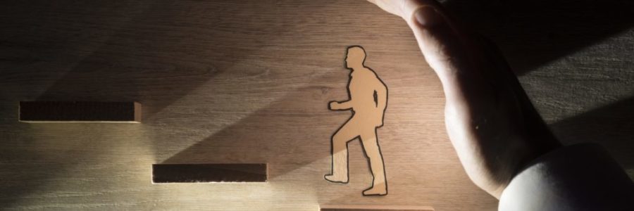 Hand protecting a paper man during progress Hand protecting a paper man during progress