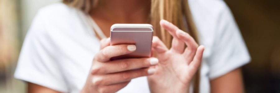 Close-up image of young blonde girl texting with smartphone