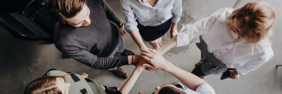 Team Building. The group of colleagues stand in a circle folded their hands together on each other Team Building. The group of colleagues stand in a circle folded their hands together on each other