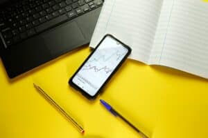 A table with a laptop, a notebook and a phone showing statistics