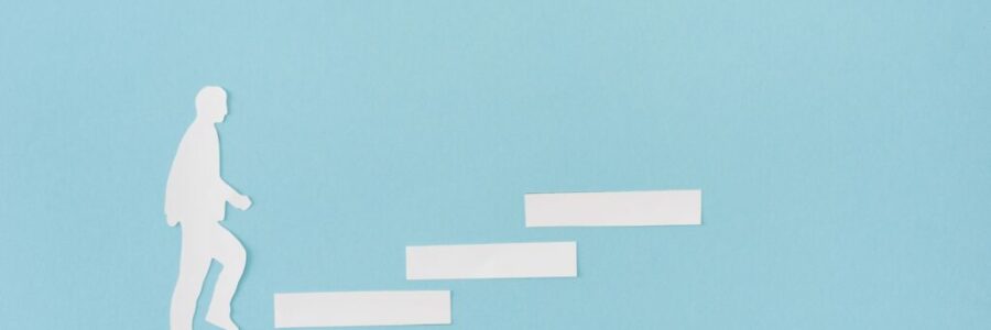 Top view of paper man on career ladder on blue Top view of paper man on career ladder on blue